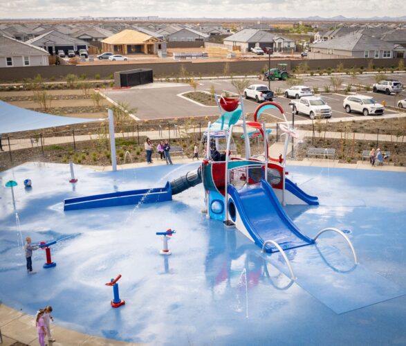 Children playing at a colorful splash pad with slides and sprayers in Apache Junction, AZ