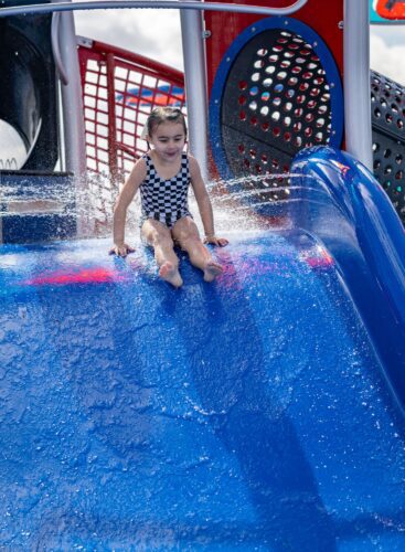 Child sliding down slide at splash pad in Apache Junction, AZ
