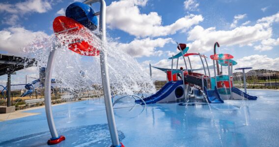 Water cascading from bucket at colorful splash pad with slides in Apache Junction, AZ