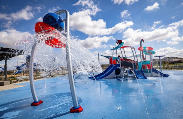 Water cascading from bucket at colorful splash pad with slides in Apache Junction, AZ