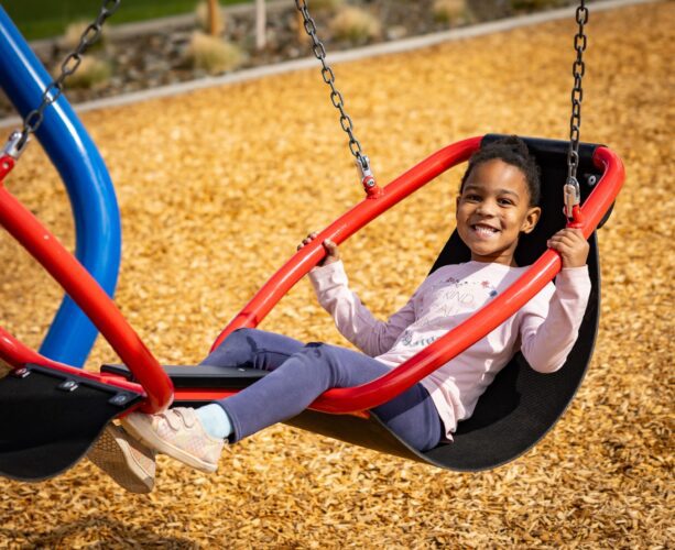 Child on two-person swing at playground in Apache Junction, AZ