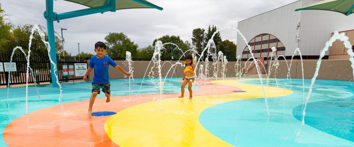 Children play at outdoor splash pad park