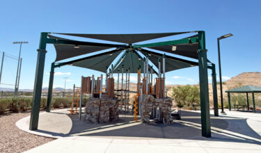 Commercial playground at Olympia Sports Park in Las Vegas, NV with shade, net climbers, slides, and site amenities.
