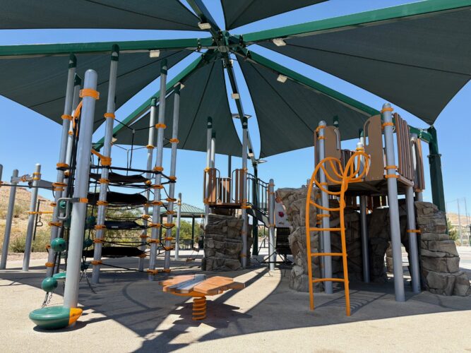 Commercial playground at Olympia Sports Park in Las Vegas, NV with shade, net climbers, slides, and site amenities.