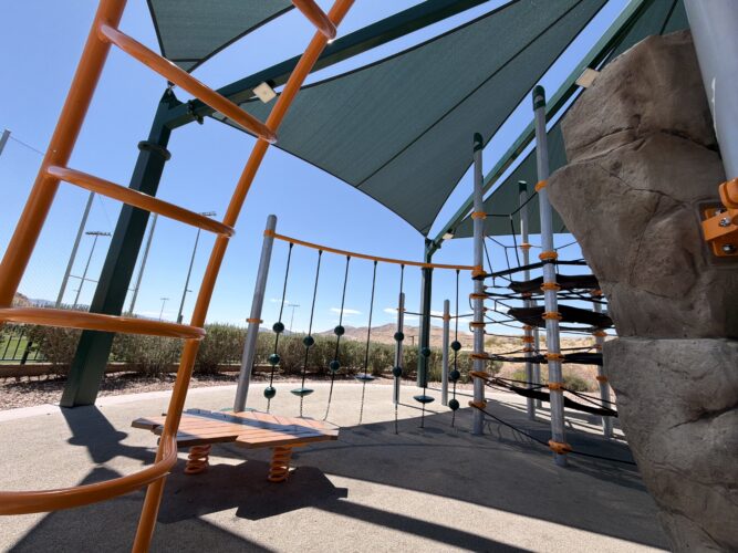 Commercial playground at Olympia Sports Park in Las Vegas, NV with shade, net climbers, slides, and site amenities.