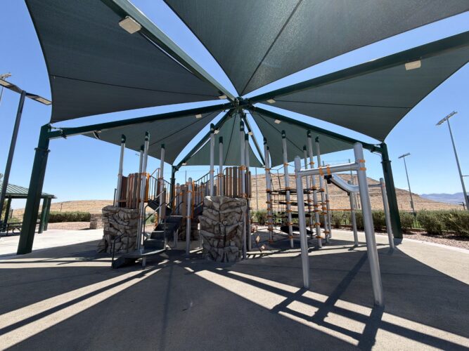 Commercial playground at Olympia Sports Park in Las Vegas, NV with shade, net climbers, slides, and site amenities.