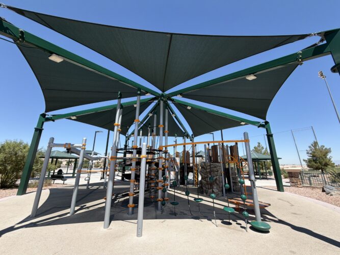 Commercial playground at Olympia Sports Park in Las Vegas, NV with shade, net climbers, slides, and site amenities.