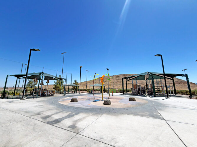 Commercial playground at Olympia Sports Park in Las Vegas, NV with shade, net climbers, slides, and site amenities.