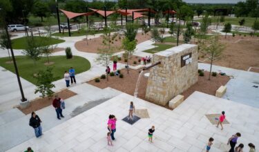 Children play at a splash pad at District 1876, Coleman, Texas.
