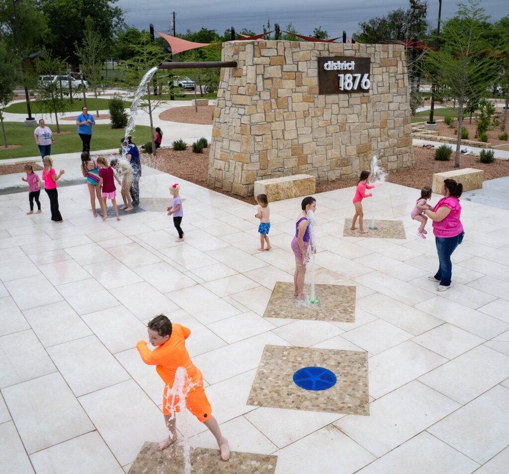 Children play at a splash pad at District 1876, Coleman, Texas.