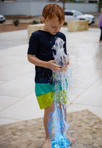 Child plays at splash pad at District 1876, Coleman, Texas.