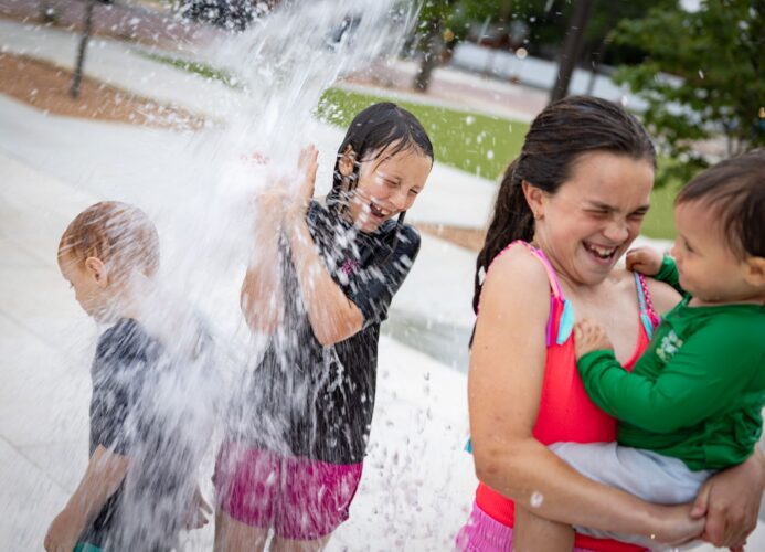 Children laugh and play at splash pad at District 1876, Coleman, Texas.