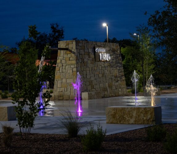 Nighttime scene of splash pad with multicolored lights at District 1876, Coleman, Texas.
