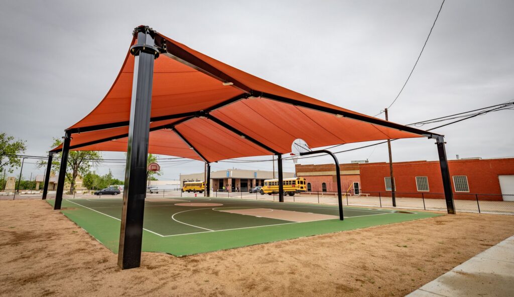 A basketball court at District 1876 in Coleman, TX with a large shade covering the court.