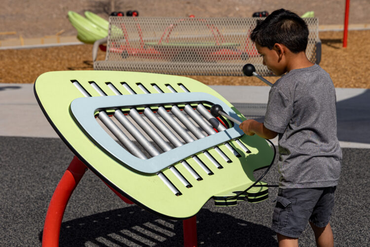 Child plays with brightly colored outdoor musical instruments at East Mesa Public Recreation Complex, in Las Cruces, New Mexico