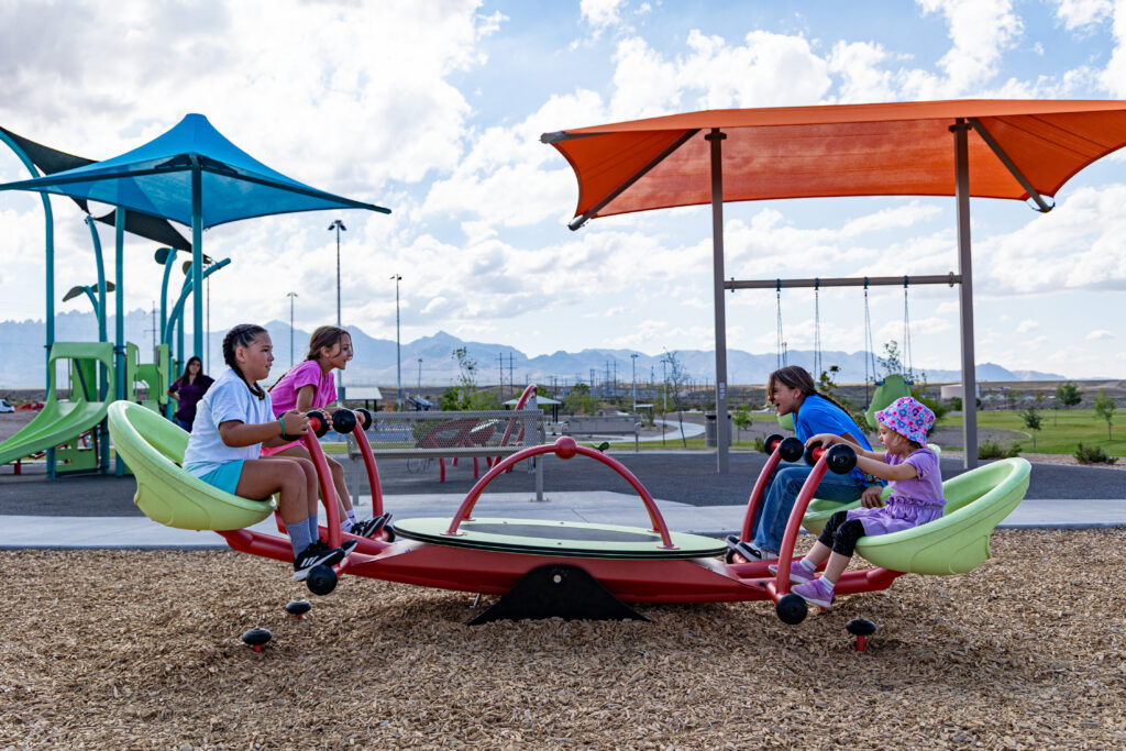 Children play at colorful playground with four person seesaw at East Mesa Public Recreation Complex, in Las Cruces, New Mexico
