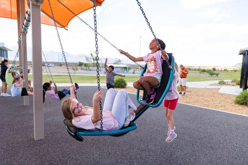 Children swing on two-person swing at East Mesa Public Recreation Complex, in Las Cruces, New Mexico